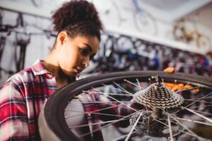 Femme réparant une roue de vélo dans un atelier de mécanique.